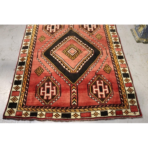 1049 - Hand knotted wool carpet, of red ground with two diamond guls, approx 301cm x 152cm