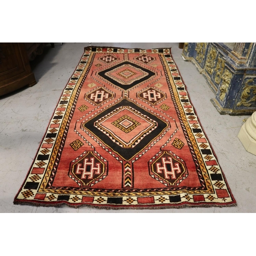 1049 - Hand knotted wool carpet, of red ground with two diamond guls, approx 301cm x 152cm