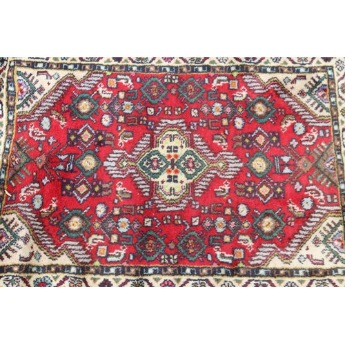 1188 - Handwoven red ground carpet, approx 63cm x 87cm