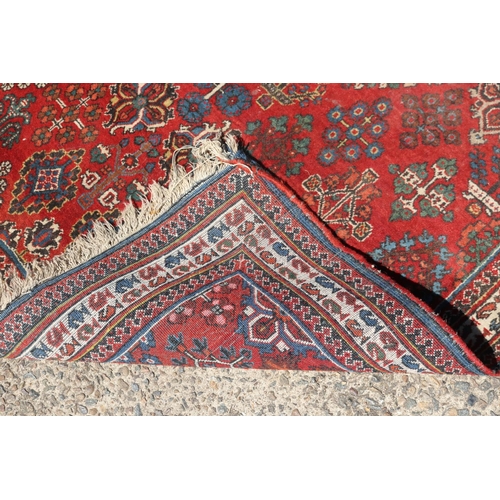 1249 - Handwoven wool carpet of red ground, approx 153cm x 107cm