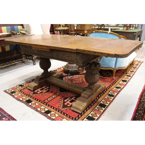 1250 - Antique English oak extension dining table, held with large carved baluster supports, with central f... 