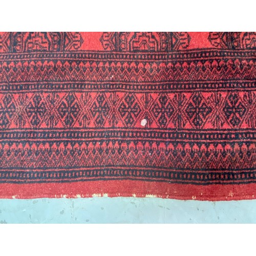 1254 - Handwoven wool carpet of red ground, approx 124cm x 196cm