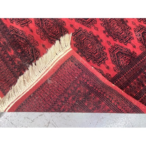 1254 - Handwoven wool carpet of red ground, approx 124cm x 196cm