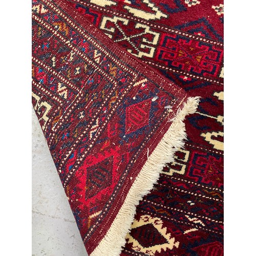 1302 - Handwoven wool carpet of red ground, approx 92cm x 135cm