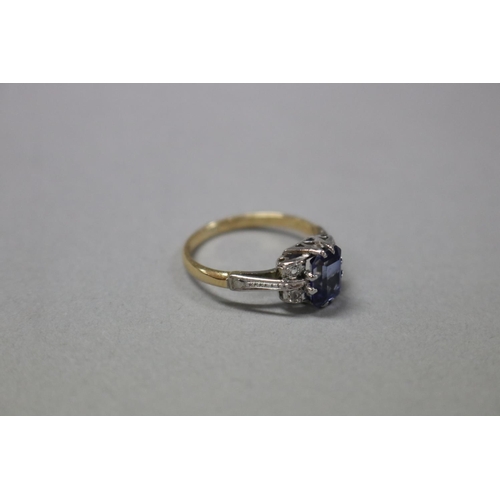 1252 - RETURNED 13/7/24 - 18ct white and yellow gold ring, claw set created emerald cut sapphire flanked by... 