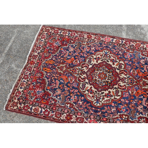 1130 - Large Persian handwoven wool carpet of red ground with central medallion, approx 315cm L x 207cm W