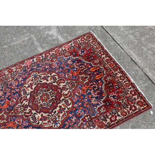 1130 - Large Persian handwoven wool carpet of red ground with central medallion, approx 315cm L x 207cm W