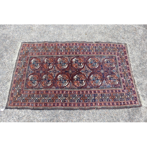 1159 - Persian handwoven wool carpet of red ground, central bosses, approx 196cm x 121cm