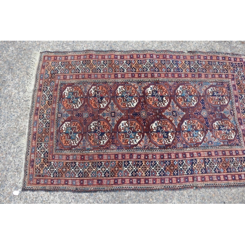 1159 - Persian handwoven wool carpet of red ground, central bosses, approx 196cm x 121cm