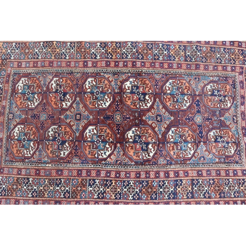 1159 - Persian handwoven wool carpet of red ground, central bosses, approx 196cm x 121cm