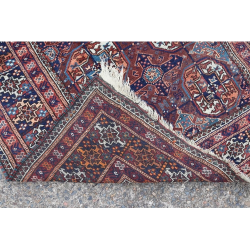 1159 - Persian handwoven wool carpet of red ground, central bosses, approx 196cm x 121cm