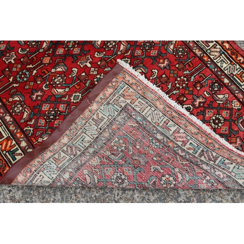 1163 - Persian handwoven wool carpet of red ground, with traditional border, approx 116cm x 339cm