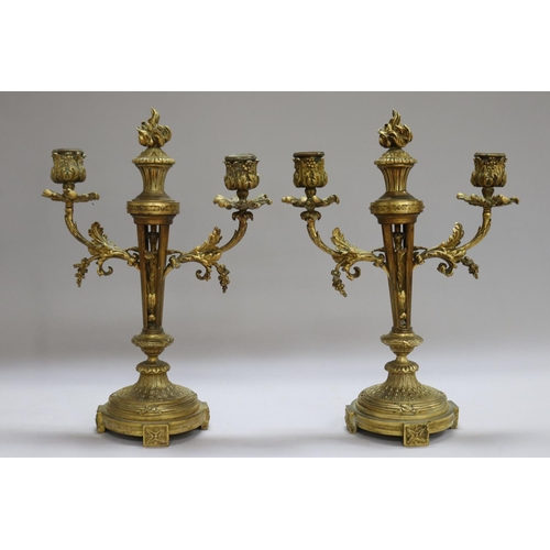 1326 - Pair of antique French Louis XVI revival bronze two stick candelabra, each with central flaming torc... 