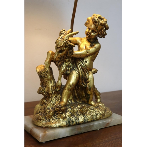 1067 - Figural gilt metal putto with goat lamp on marble base, with shade, in working condition at time of ... 