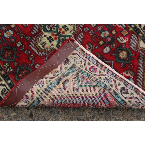 1107 - Persian Hand woven red ground carpet, approx 63cm x 87cm