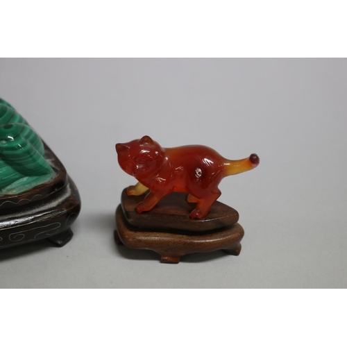 114 - Chinese Malachite carving of a frog, a crystal carved pig and a carnelian cat all on wooden stands, ... 