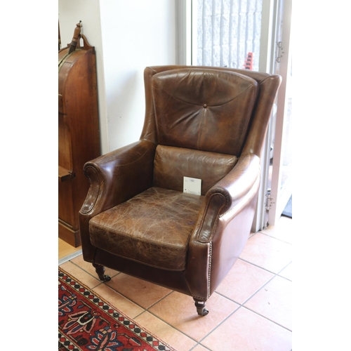 1022 - Good quality brown leather armchair, with brass studded trim, turned legs with brass castors, approx... 