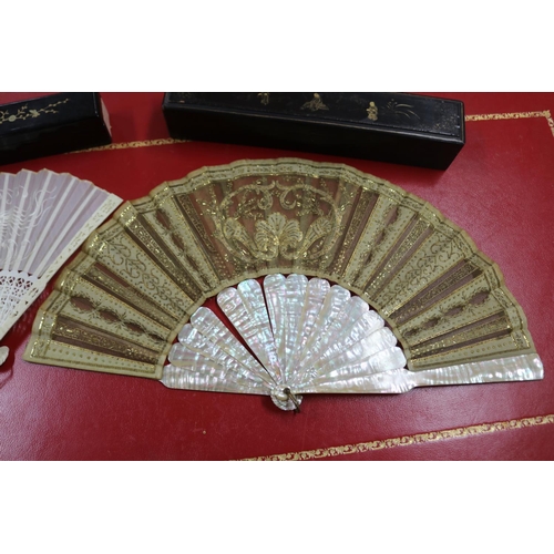 304 - Two Chinese export fans in lacquer cases, one with mother of pearl sticks & the other with pierced b... 