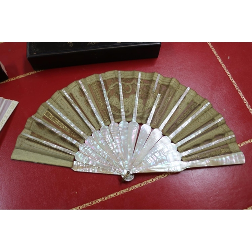 304 - Two Chinese export fans in lacquer cases, one with mother of pearl sticks & the other with pierced b... 