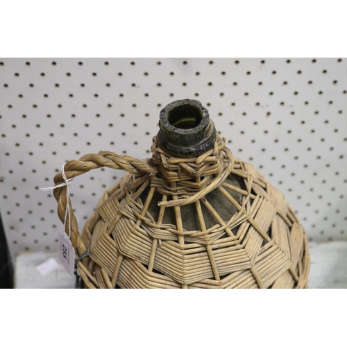 5020 - Glass jar in woven cover with handle, approx 32cm H