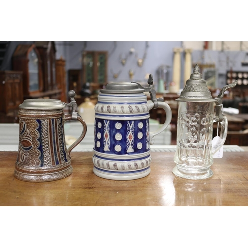 5139 - Two German pottery tankards along with a glass tankard, approx 22cm H and shorter (3)