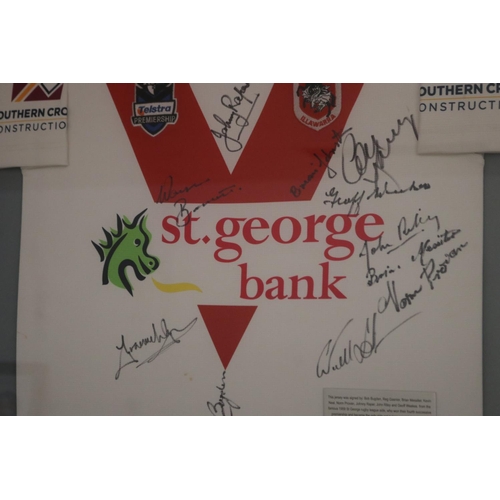 1410 - Framed & signed St George Dragons jersey.

Plaque reads: This jersey was signed by: Bob Bugden, Reg ... 