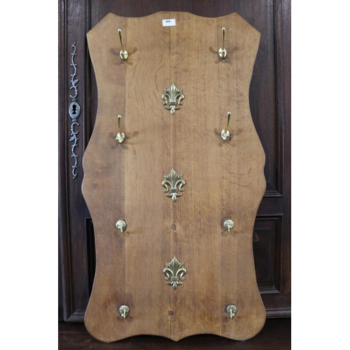 489 - Oak shield shaped coat rack, fitted with eight brass hooks, approx 98cm H x 52cm W