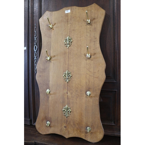 489 - Oak shield shaped coat rack, fitted with eight brass hooks, approx 98cm H x 52cm W