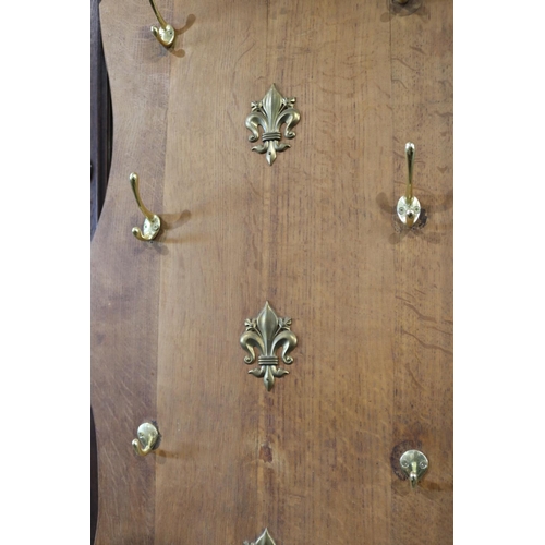 489 - Oak shield shaped coat rack, fitted with eight brass hooks, approx 98cm H x 52cm W