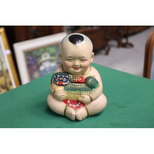 501 - Money box in the form of a Chinese boy holding a foo dog, approx 18cm H