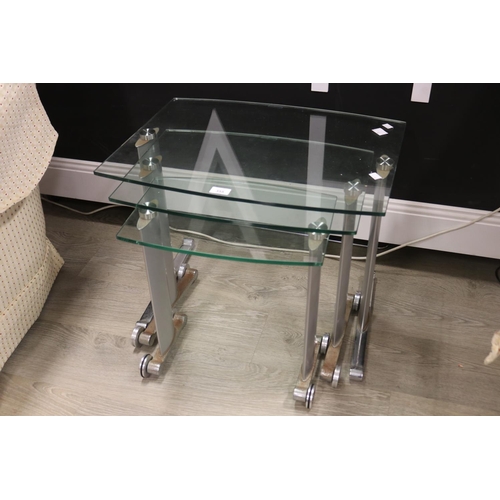 355 - Set of three glass and chrome nest of tables with steel roller feet, approx 49cm H x 60cm W x 46cm D... 
