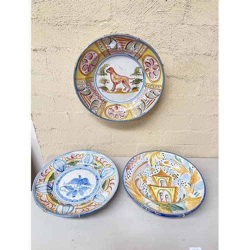 360 - Three antique Portuguese tin glazed pottery wall plates, decorated with Hound, buildings, blue bird ... 