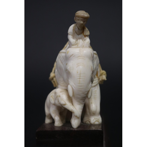 11 - Well carved ivory figure of an elephant pulling a log, with rider to top. Standing on wooden base. S... 