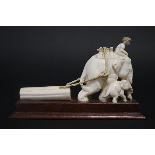 11 - Well carved ivory figure of an elephant pulling a log, with rider to top. Standing on wooden base. S... 