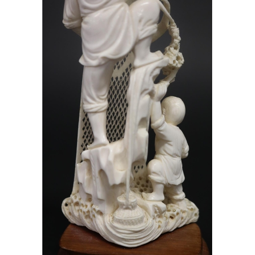 23 - Finely carved ivory figure of an old fisherman hauling in his net, with young boy, standing on woode... 