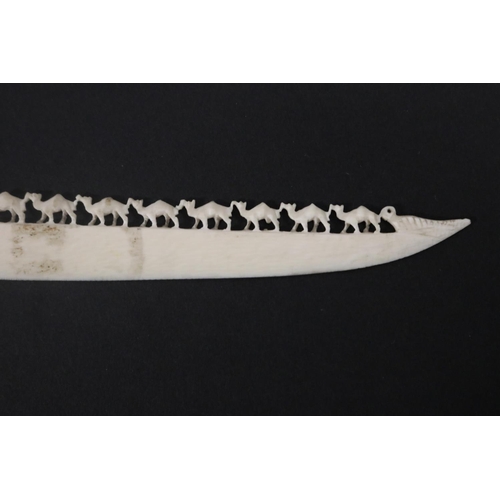 115 - Carved ivory letter opener, carved with chains of camels, approx 16cm L