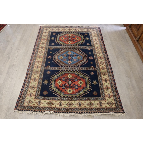 292 - Caucasian hand knotted wool carpet, three central guls on a blue ground, approx 201cm x 140cm