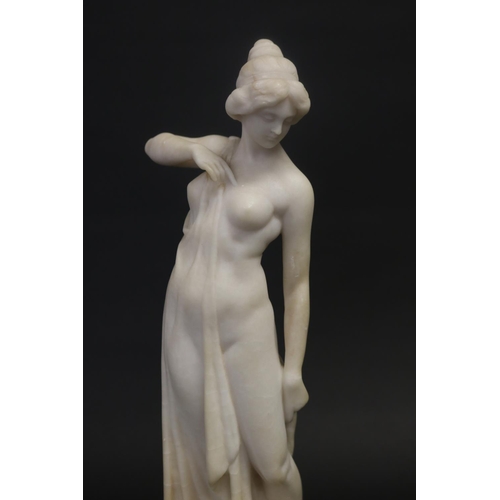 450 - Antique carved alabaster figure of a semi clad female, standing on a black marble base, unsigned. Ap... 
