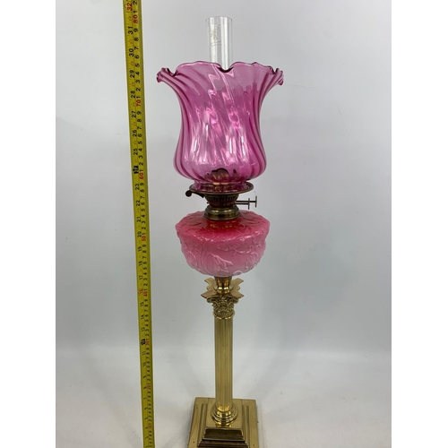 16 - Large Victorian style ruby oil lamp with Corinthian style pillar, 83cm