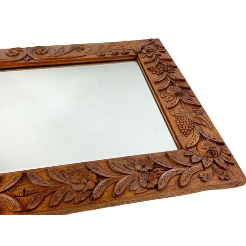 200 - An Arts & Crafts carved oak framed bevelled mirror. Circa 1900. 71 x 51cm.