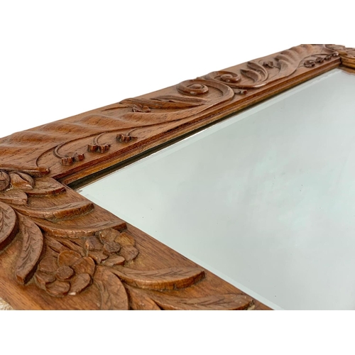 200 - An Arts & Crafts carved oak framed bevelled mirror. Circa 1900. 71 x 51cm.