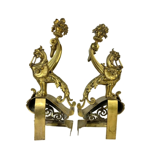 324u - A pair of large early 20th century ornate brass andirons in the form of griffins. 53cm.