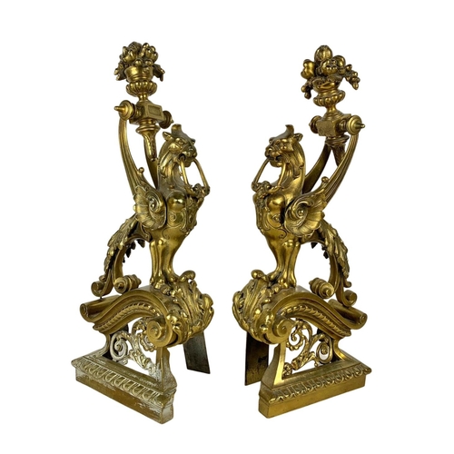 324u - A pair of large early 20th century ornate brass andirons in the form of griffins. 53cm.