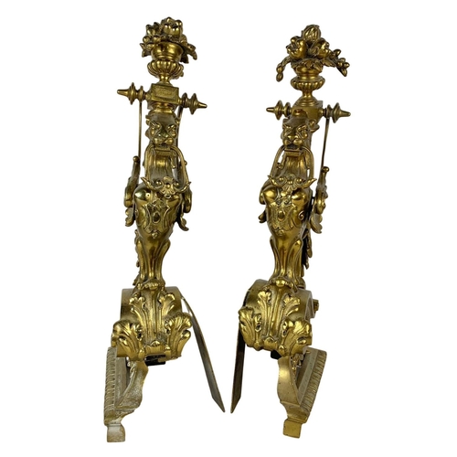 324u - A pair of large early 20th century ornate brass andirons in the form of griffins. 53cm.