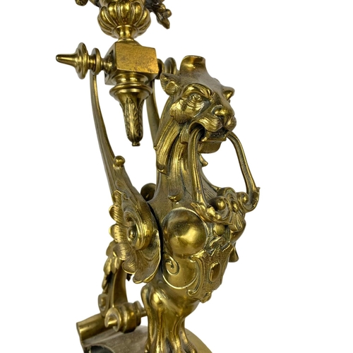 324u - A pair of large early 20th century ornate brass andirons in the form of griffins. 53cm.