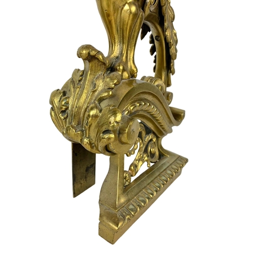 324u - A pair of large early 20th century ornate brass andirons in the form of griffins. 53cm.