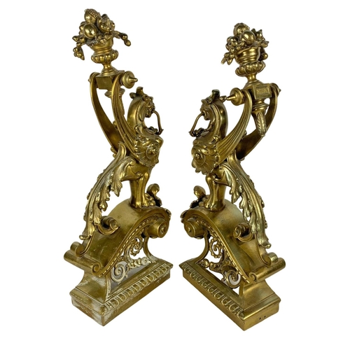 324u - A pair of large early 20th century ornate brass andirons in the form of griffins. 53cm.