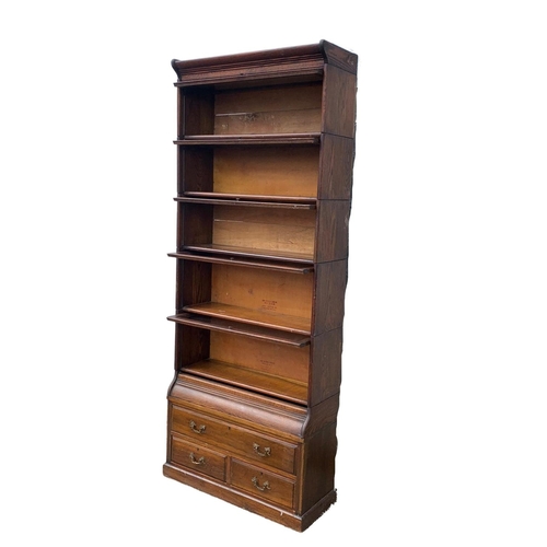 1004 - A large Edwardian oak stacking bookcase by Gumm. 87 x 35 x 221cm.