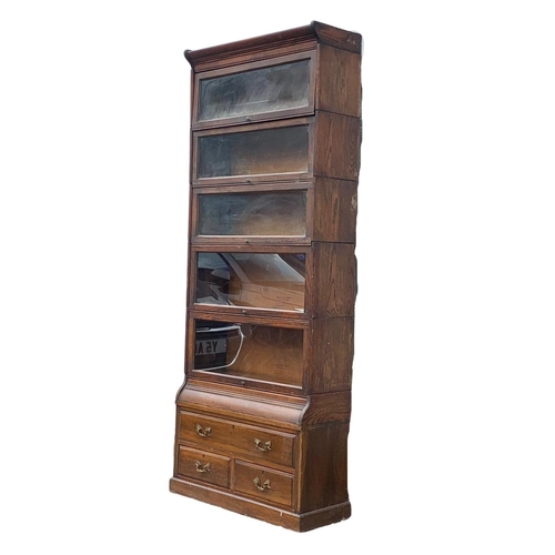 1004 - A large Edwardian oak stacking bookcase by Gumm. 87 x 35 x 221cm.