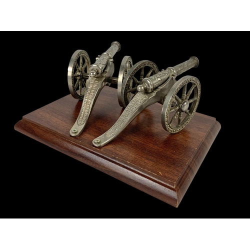 568 - A pair of silver plated cannons on a wooden plinth. 20.5 x 15.5 x 9cm.